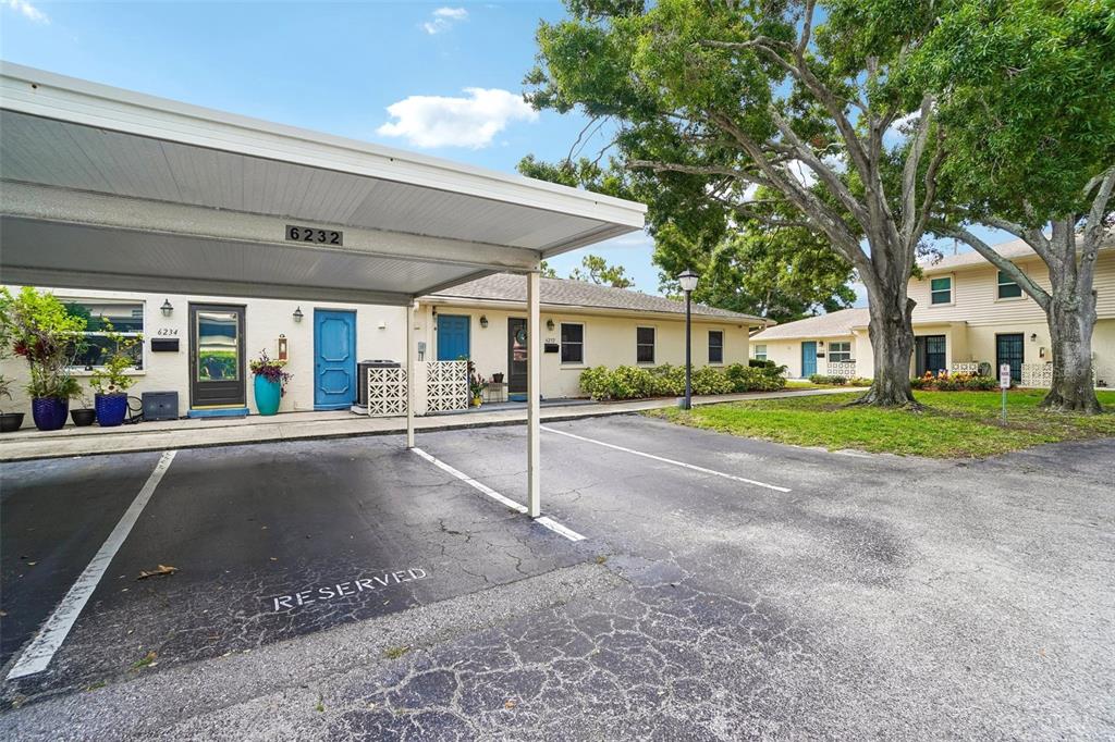 A covered parking space sits in front of a single-story apartment building with tan siding — 6232 GRETNA GREEN COURT N, PINELLAS PARK, FL