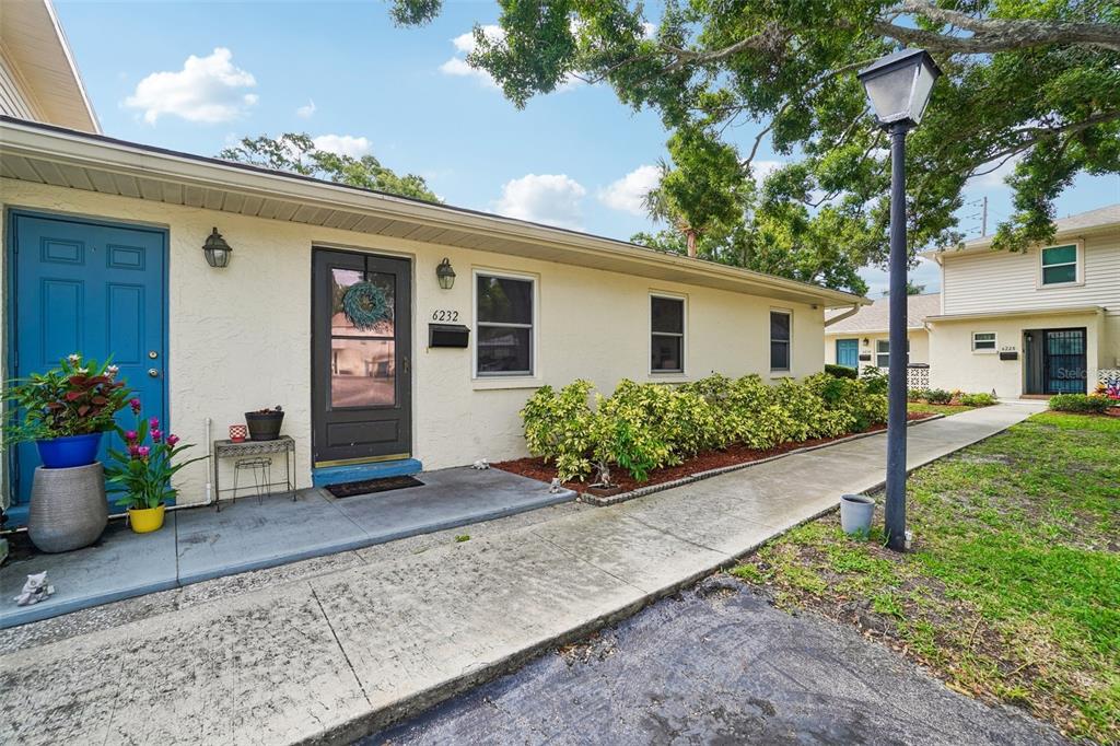 A single-story building with a blue door, a dark front door, and a concrete walkway — 6232 GRETNA GREEN COURT N, PINELLAS PARK, FL