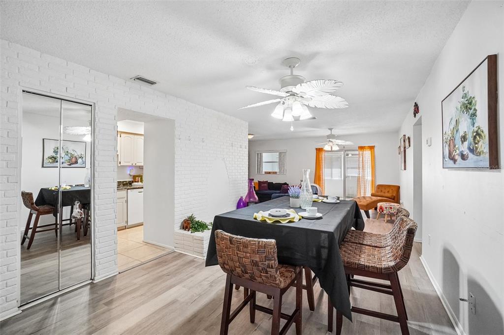A dining area features a black-clothed table, wicker chairs, and a white brick accent wall — 6232 GRETNA GREEN COURT N, PINELLAS PARK, FL