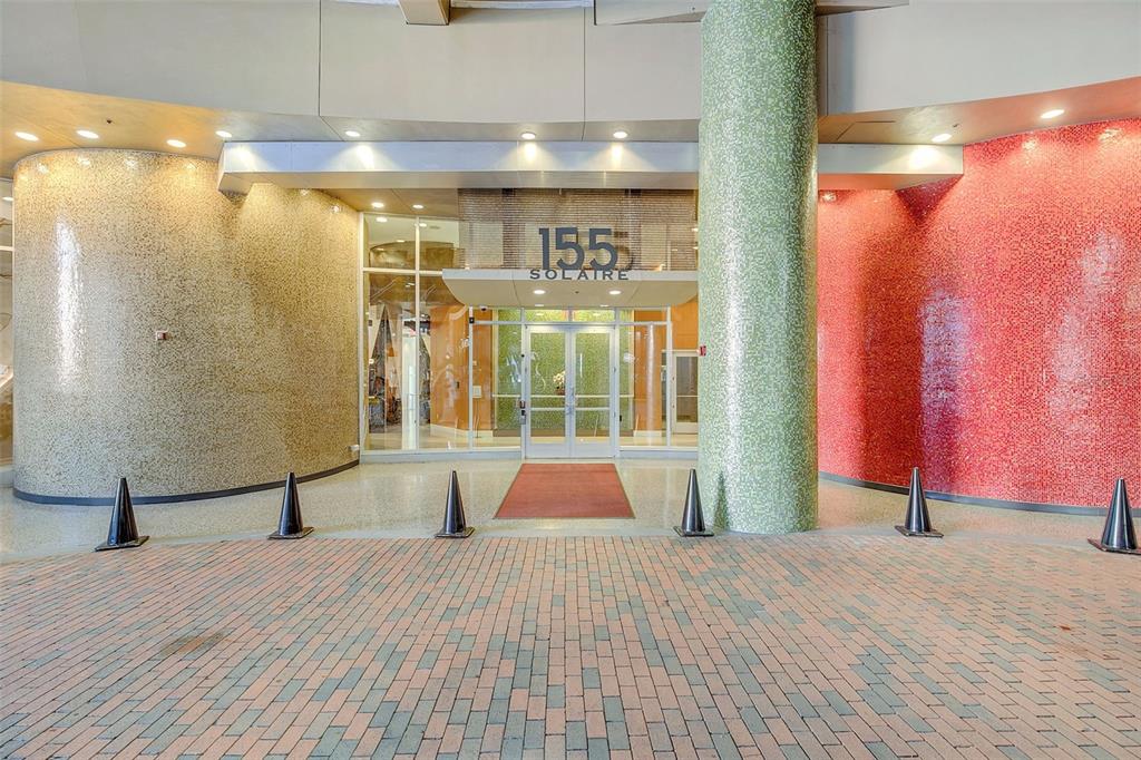 The exterior entrance of a building features a brick driveway, glass doors, and tiled walls — 155 S COURT AVENUE UNIT 2705, ORLANDO, FL