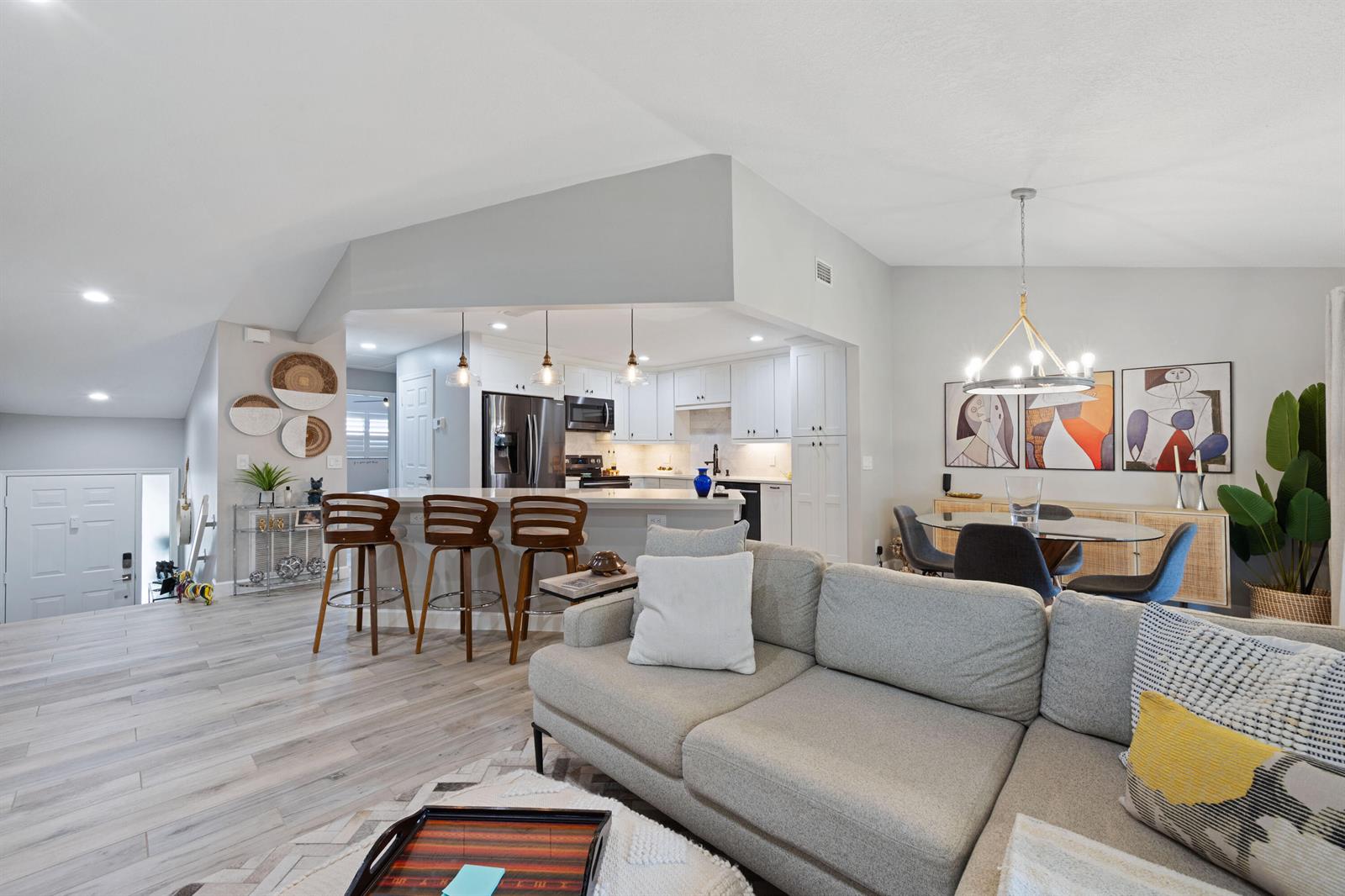 An open-concept living area features a gray sectional sofa, kitchen island with barstools, and dining — 5710 Coach House Circle # F, Boca Raton FL 33486, BOCA RATON, FL