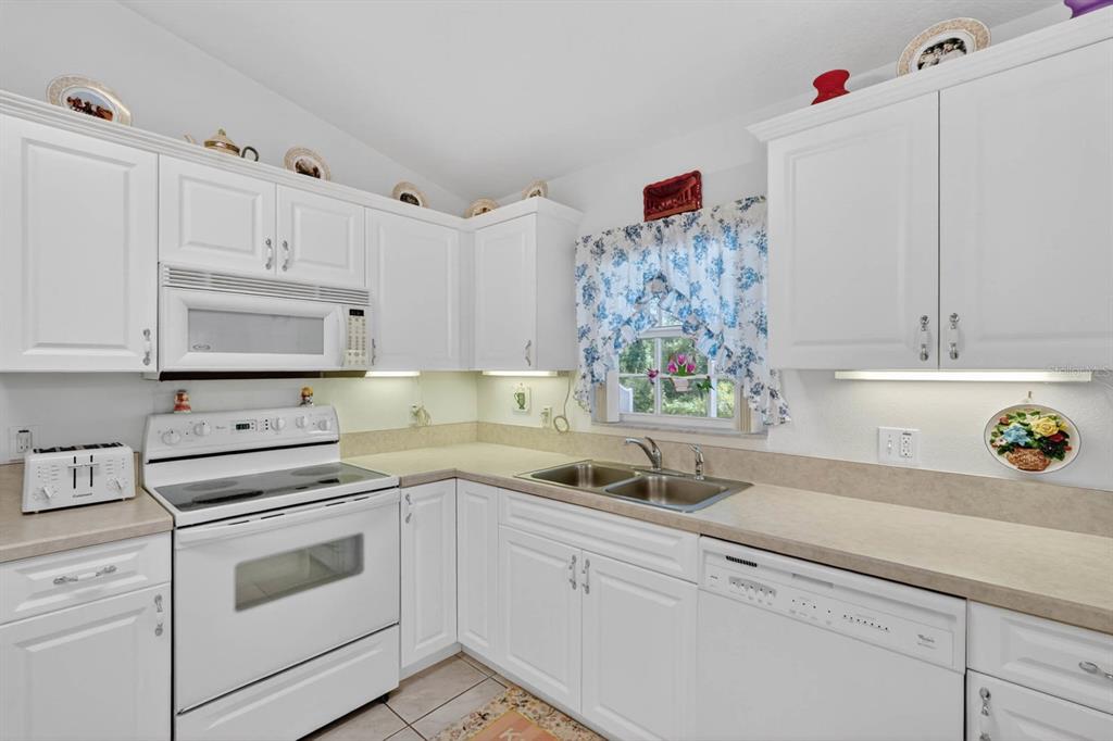 A kitchen with white cabinets, white appliances, a double sink, and a floral valance — 80 ROXBORO, PALM COAST, FL