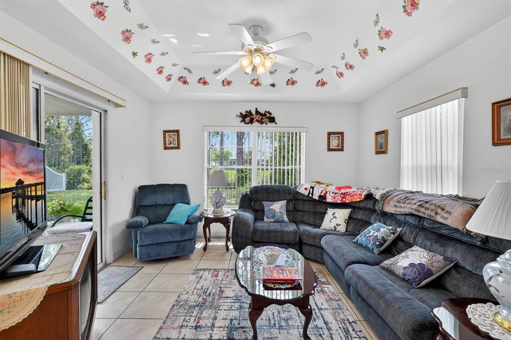 A living room features a sectional sofa, a recliner, a glass coffee table, and floral ceiling — 80 ROXBORO, PALM COAST, FL
