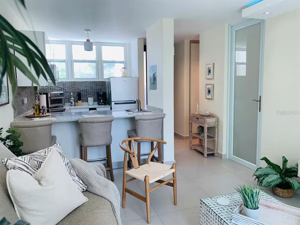 A kitchen with a breakfast bar and stools opens into a living area with tile flooring — 1300 ASHFORD AVENUE UNIT 3A, SAN JUAN, PR