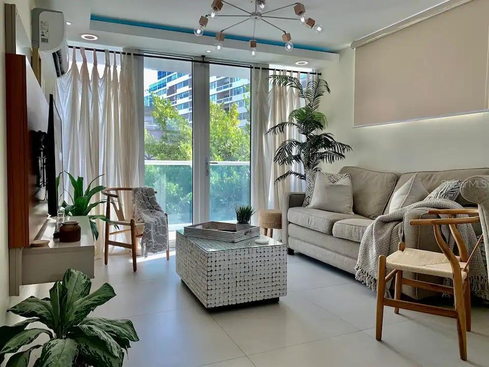 A living room features a beige sofa, a tiled coffee table, and floor-to-ceiling windows — 1300 ASHFORD AVENUE UNIT 3A, SAN JUAN, PR