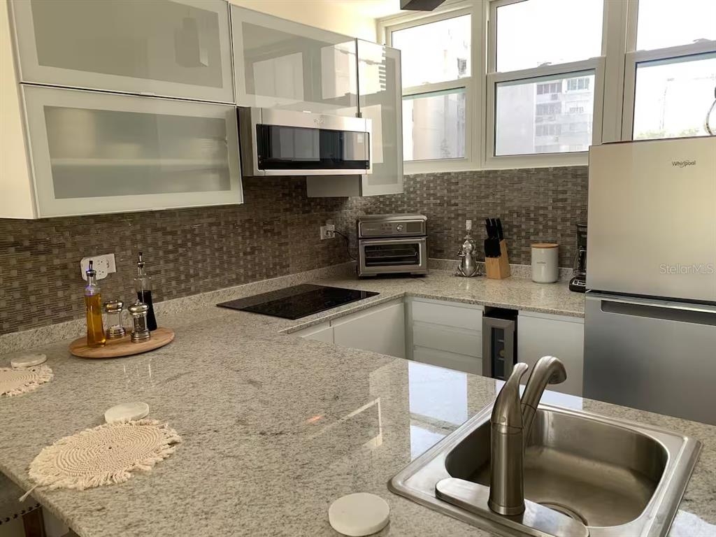 A kitchen features granite countertops, white cabinetry, stainless steel appliances, and a tiled backsplash — 1300 ASHFORD AVENUE UNIT 3A, SAN JUAN, PR