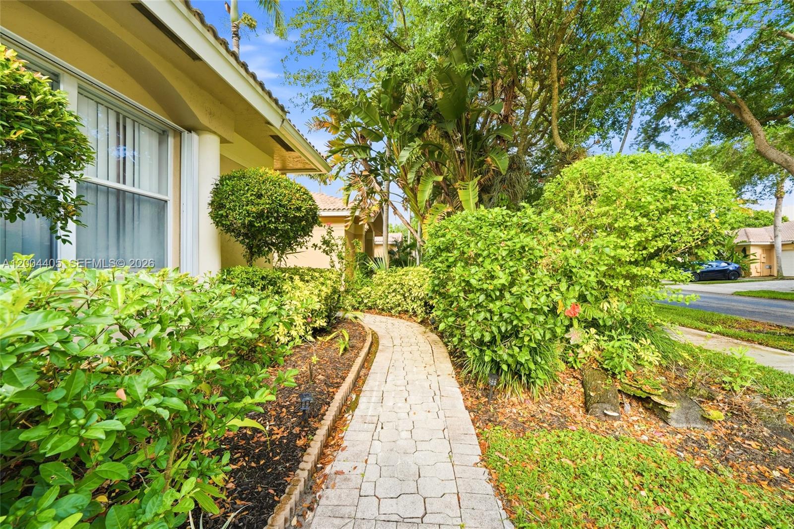 A paved walkway leads past lush landscaping toward the entrance of a residential building — 2513 Coral Trace Pl # 0, Delray Beach FL 33445, DELRAY BEACH, FL