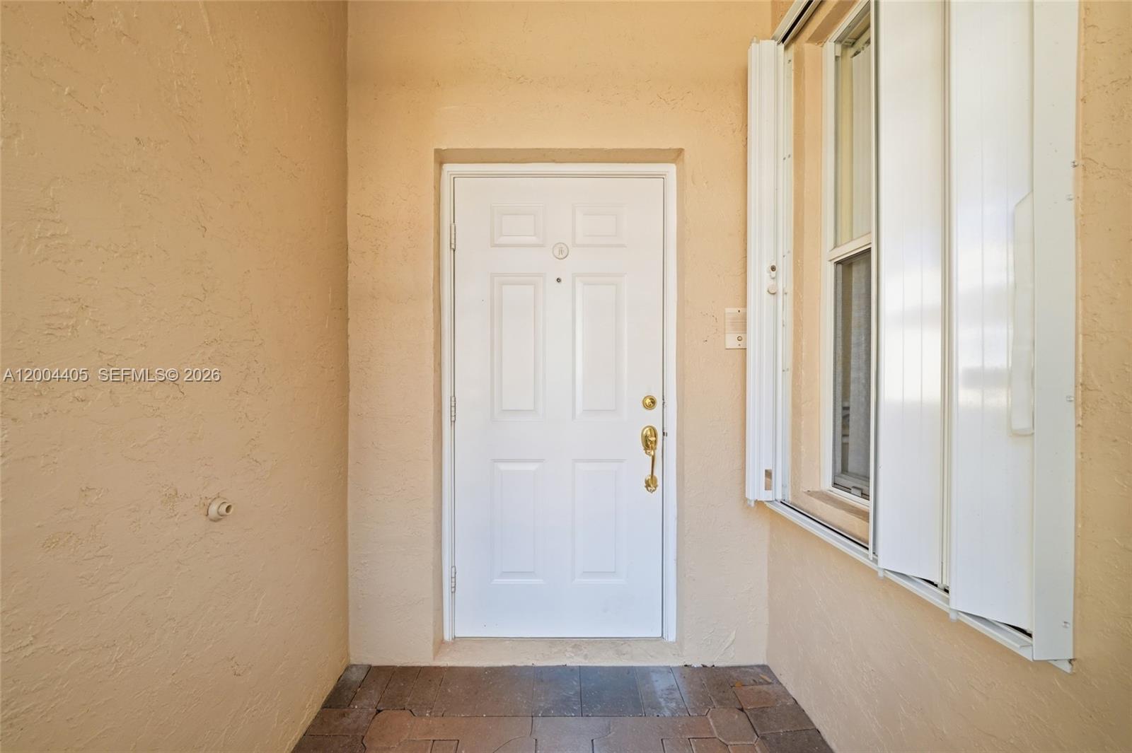 A white front door with gold hardware is set into a tan stucco entryway — 2513 Coral Trace Pl # 0, Delray Beach FL 33445, DELRAY BEACH, FL