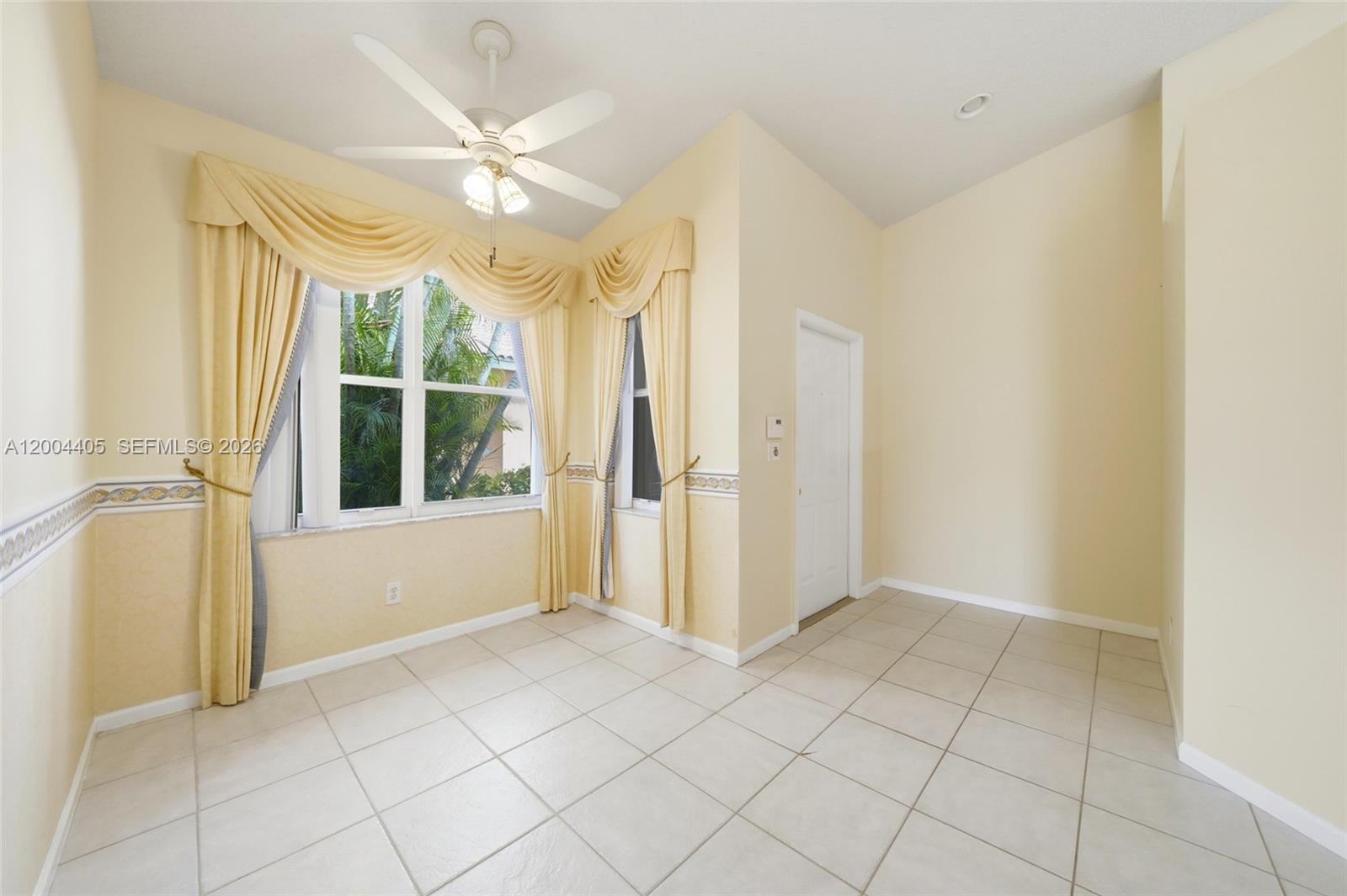 A sunlit room features light-colored tile flooring, pale yellow walls, and decorative window drapes — 2513 Coral Trace Pl # 0, Delray Beach FL 33445, DELRAY BEACH, FL