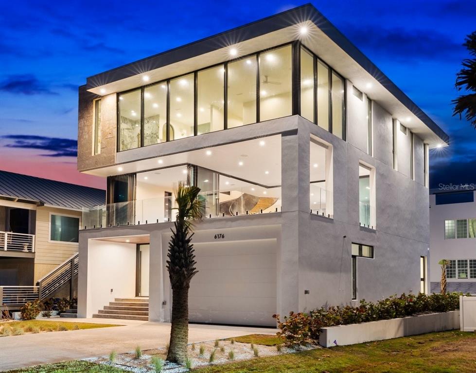 A modern three-story house with a white exterior, large glass windows, and a ground-level garage — 6176 S ATLANTIC AVENUE, NEW SMYRNA BEACH, FL