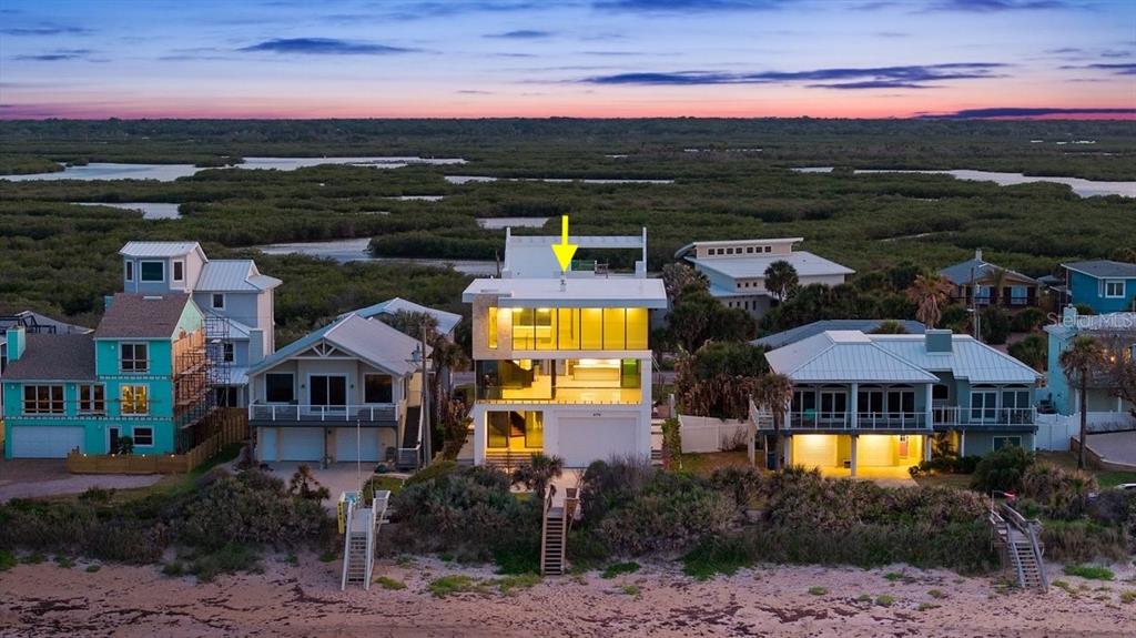 An aerial view of a modern three-story beach house with large windows and a rooftop — 6176 S ATLANTIC AVENUE, NEW SMYRNA BEACH, FL