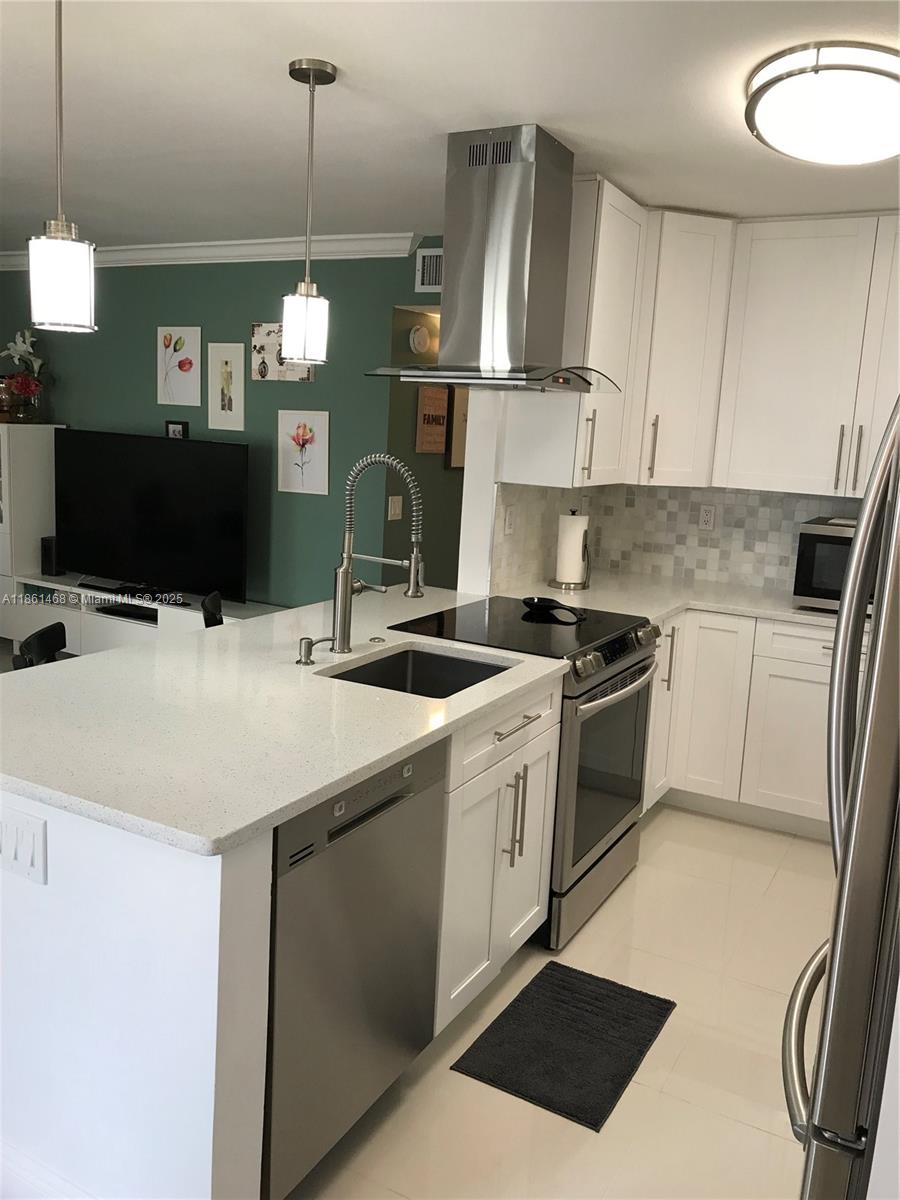 A kitchen with white cabinets, stainless steel appliances, and a quartz-topped island with a sink — 466 Normandy J # 466, Delray Beach FL 33484, DELRAY BEACH, FL