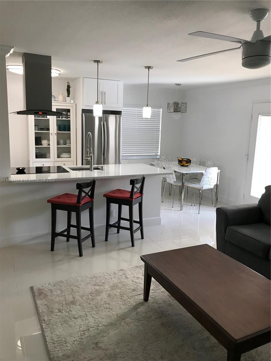 A modern kitchen with white cabinets, stainless steel appliances, and a breakfast bar with stools — 466 Normandy J # 466, Delray Beach FL 33484, DELRAY BEACH, FL