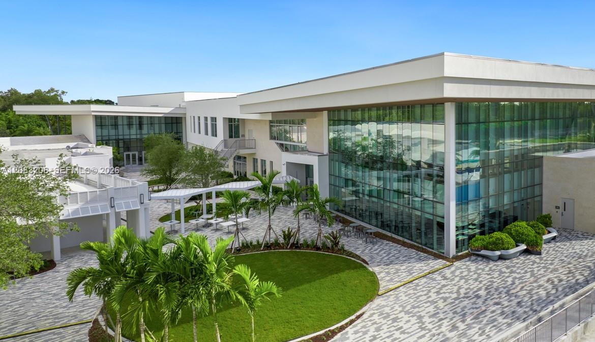 An exterior view of a modern building with large glass windows and a paved courtyard — 9059 SW 73rd Ct, Miami FL 33156, MIAMI, FL