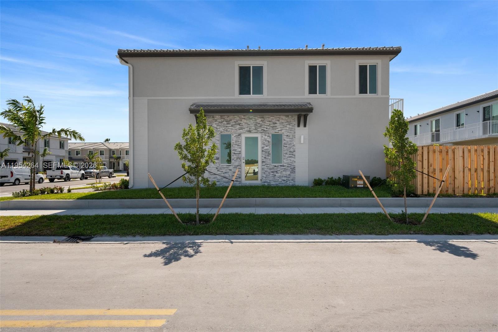 A two-story residential building features a light gray exterior with a stone-accented entryway — 716 SE 14th Ct, Homestead FL 33034, HOMESTEAD, FL