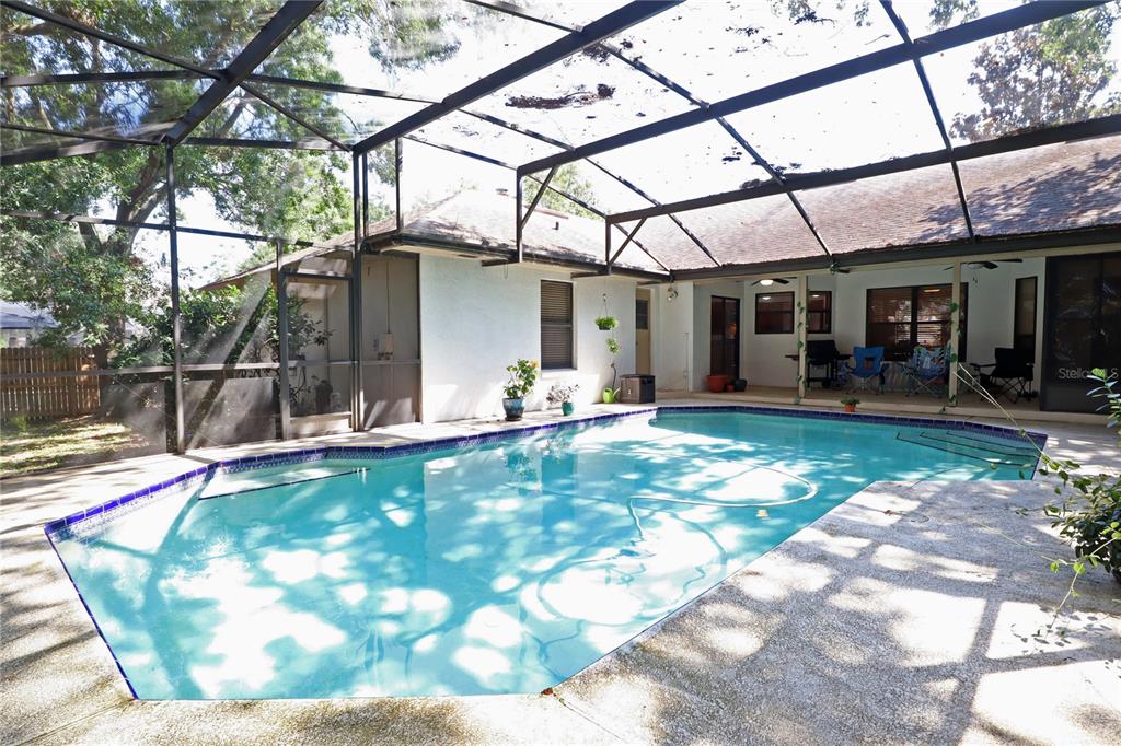 A swimming pool sits inside a screened-in patio area next to a house — 5722 BAY SIDE DRIVE, ORLANDO, FL