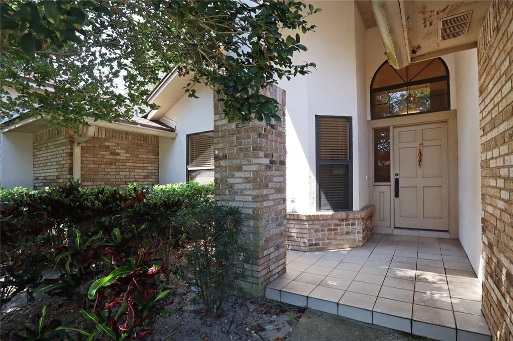 The exterior of a house features a brick pillar, a tiled porch, and a front door — 5722 BAY SIDE DRIVE, ORLANDO, FL