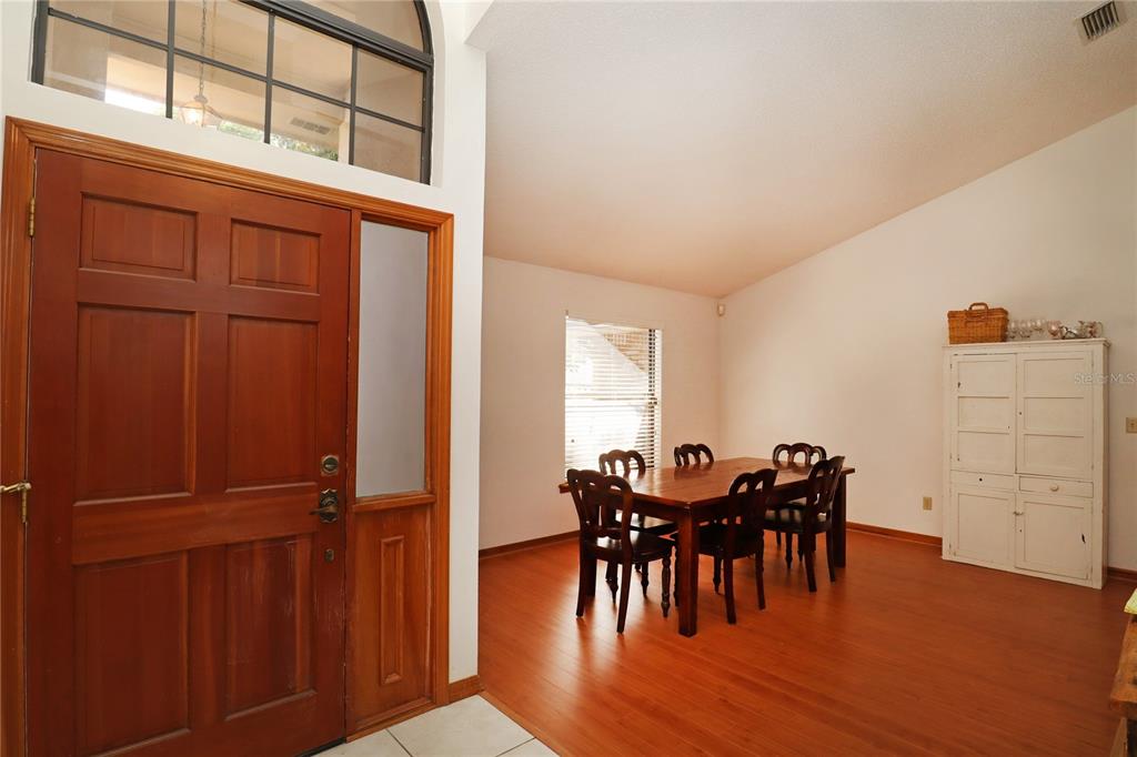 A dining room with wood flooring, a wooden table, chairs, and a white hutch — 5722 BAY SIDE DRIVE, ORLANDO, FL