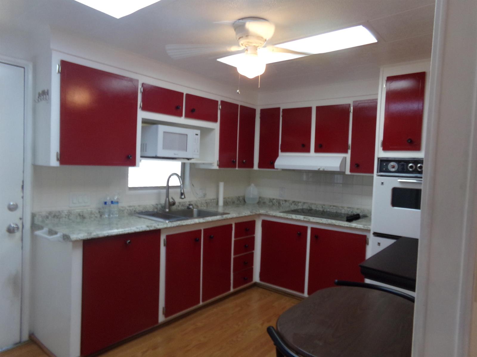A kitchen features red cabinets, white trim, light countertops, and a ceiling fan — 6385 Cypress Lane, Atlantis FL 33462, ATLANTIS, FL
