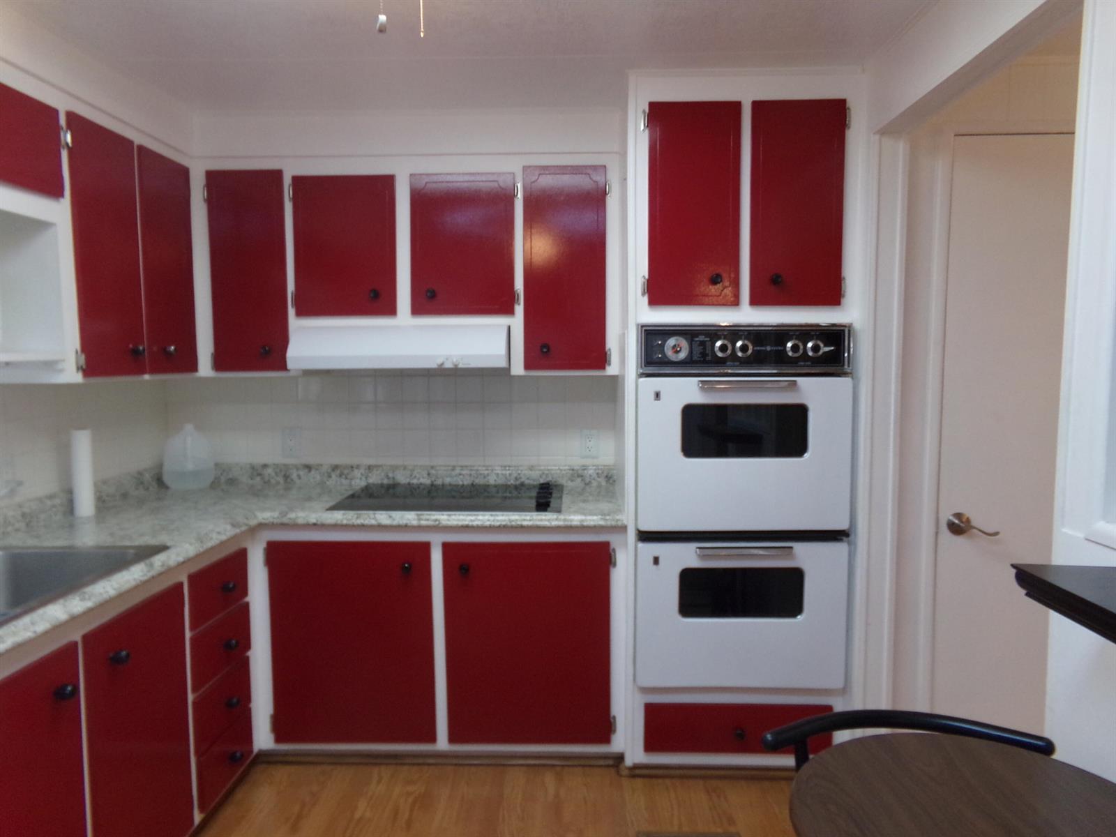 A kitchen features red cabinets, white appliances, and a speckled countertop — 6385 Cypress Lane, Atlantis FL 33462, ATLANTIS, FL