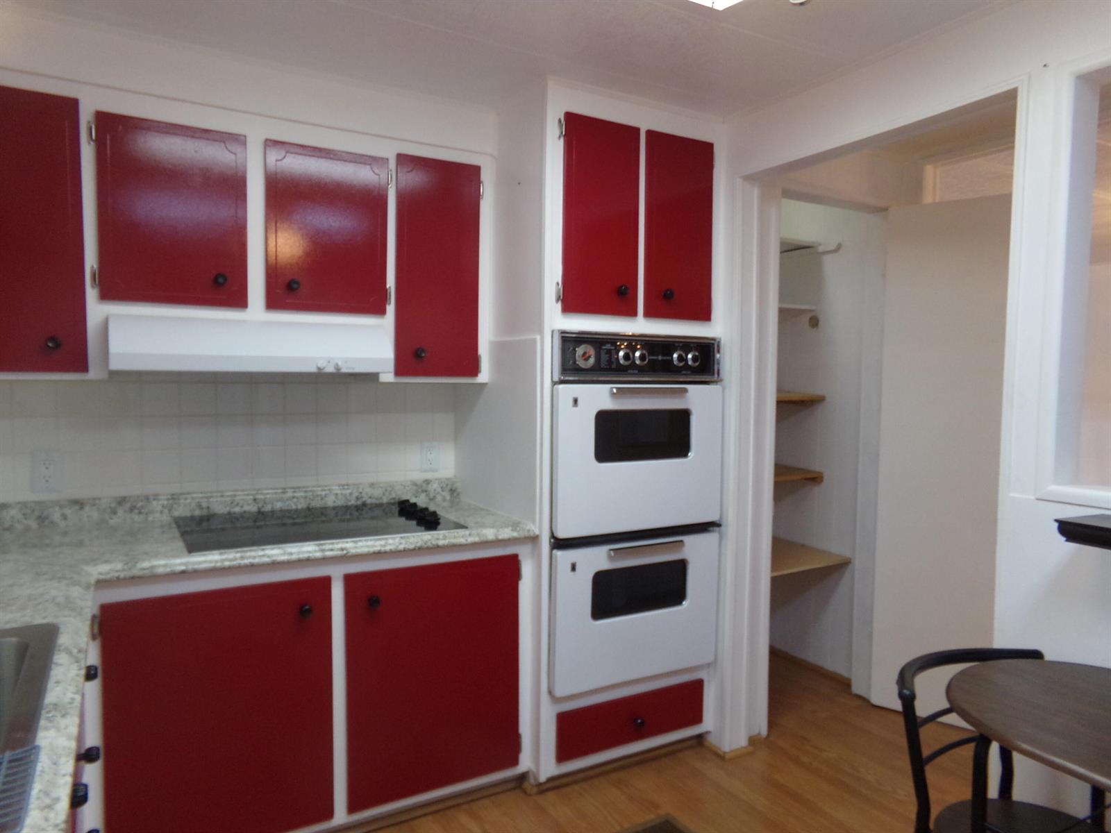 A kitchen features red cabinets, white appliances, a double wall oven, and a granite countertop — 6385 Cypress Lane, Atlantis FL 33462, ATLANTIS, FL