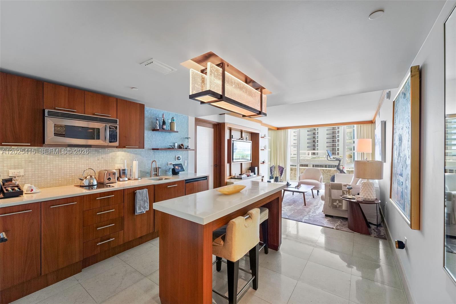 A modern kitchen with wood cabinets and a central island opens into a living area — 6801 Collins Ave # 708, Miami Beach FL 33141, MIAMI BEACH, FL