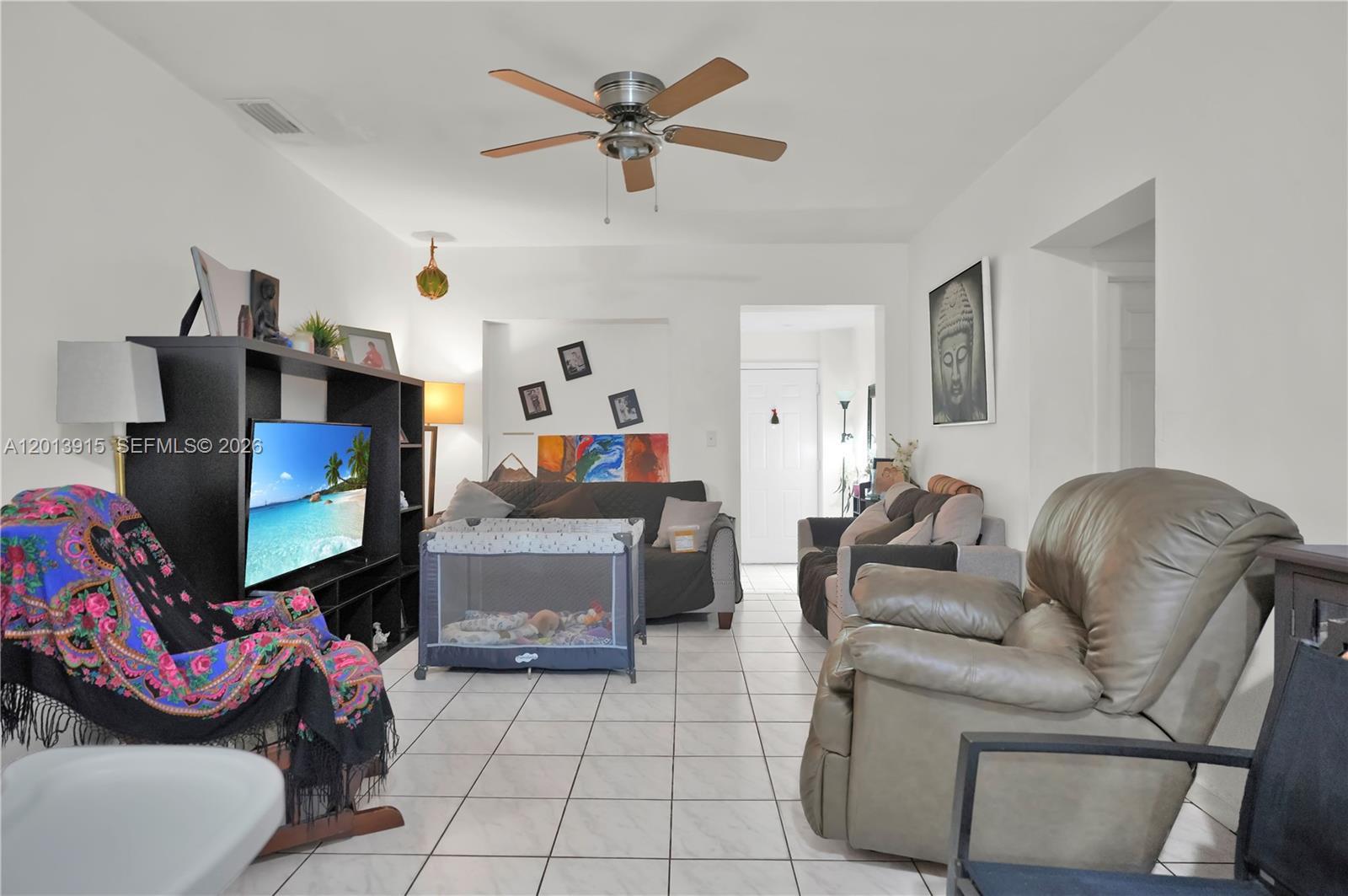 A living room features white tile floors, a ceiling fan, and a playpen — 201 NW 25th Ave, Miami FL 33125, MIAMI, FL