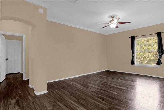 An empty room features dark wood-look flooring, beige walls, a ceiling fan, and a window — 246 VILLA DI ESTE TERRACE UNIT 200, LAKE MARY, FL