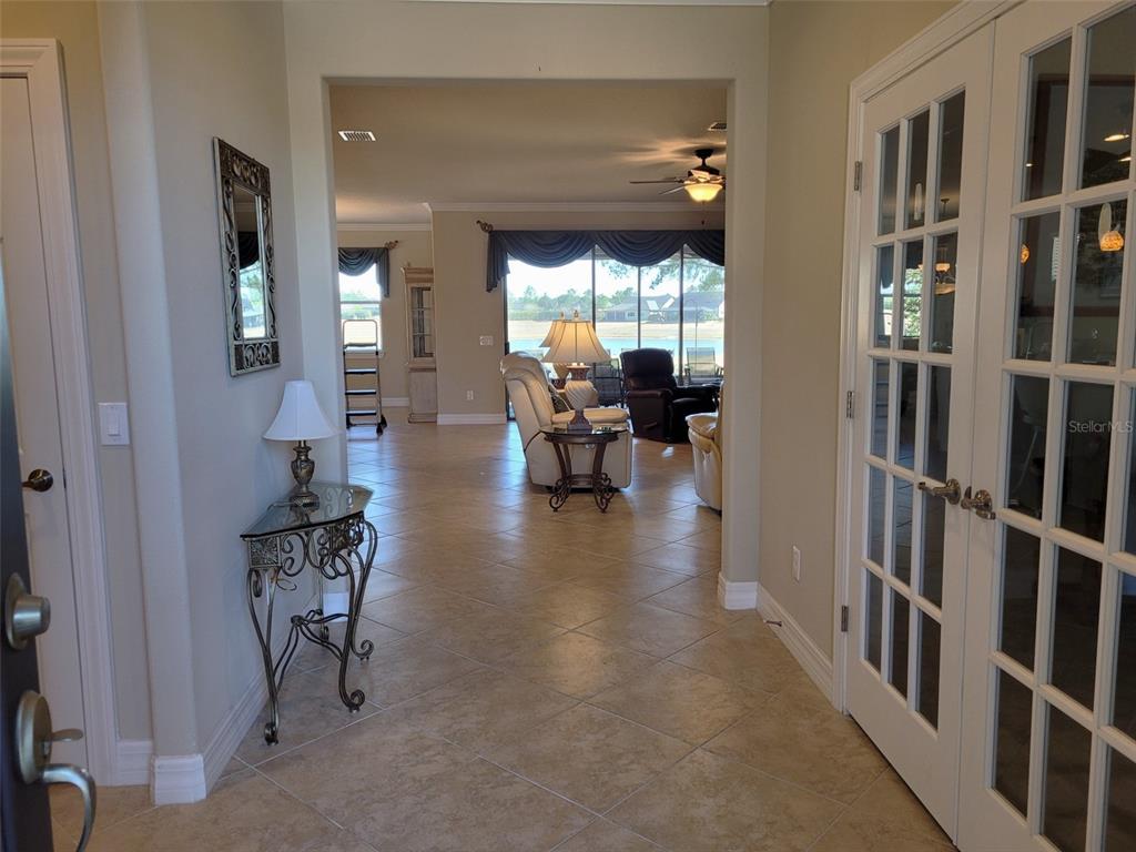 An entryway with tile flooring leads into a living room featuring a view of water — 6443 SW 97TH TERRACE ROAD, OCALA, FL