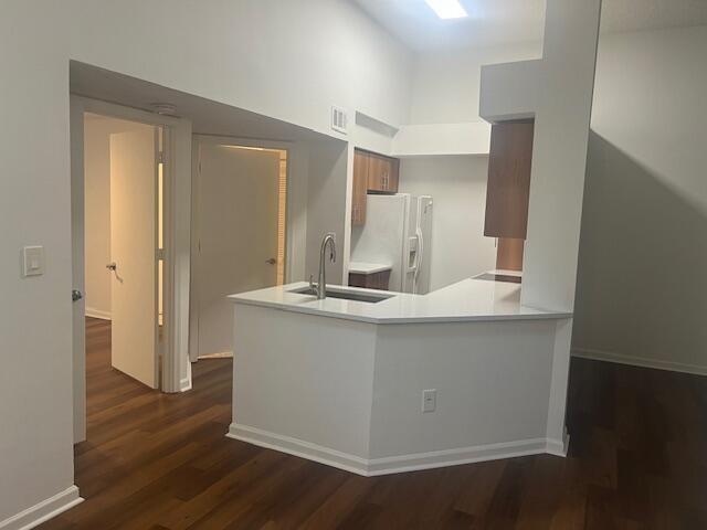 A kitchen with white countertops and cabinets opens to a hallway with wood flooring — 1050 Crystal Way # D, Delray Beach FL 33444, DELRAY BEACH, FL