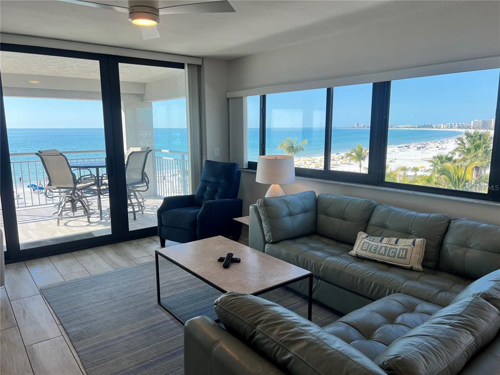 A living room with a sectional sofa, blue armchair, and a balcony overlooking the ocean — 1001 POINT OF ROCKS ROAD UNIT 512, SARASOTA, FL