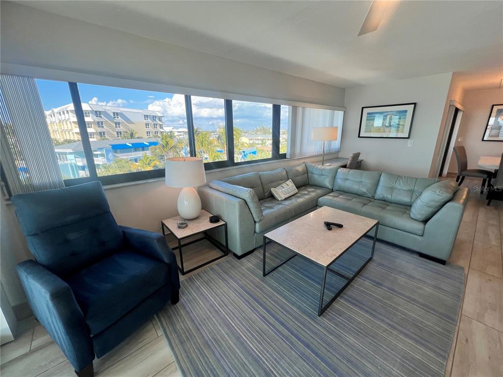 A living room features a blue recliner, a light green sectional sofa, and a coffee table — 1001 POINT OF ROCKS ROAD UNIT 512, SARASOTA, FL