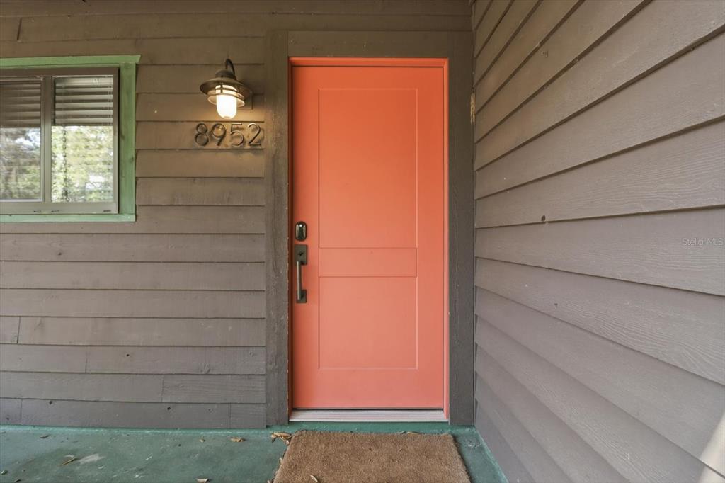 An exterior view shows a coral-colored front door next to a window with green trim — 8952 W WHITE DOGWOOD DRIVE, HOMOSASSA, FL