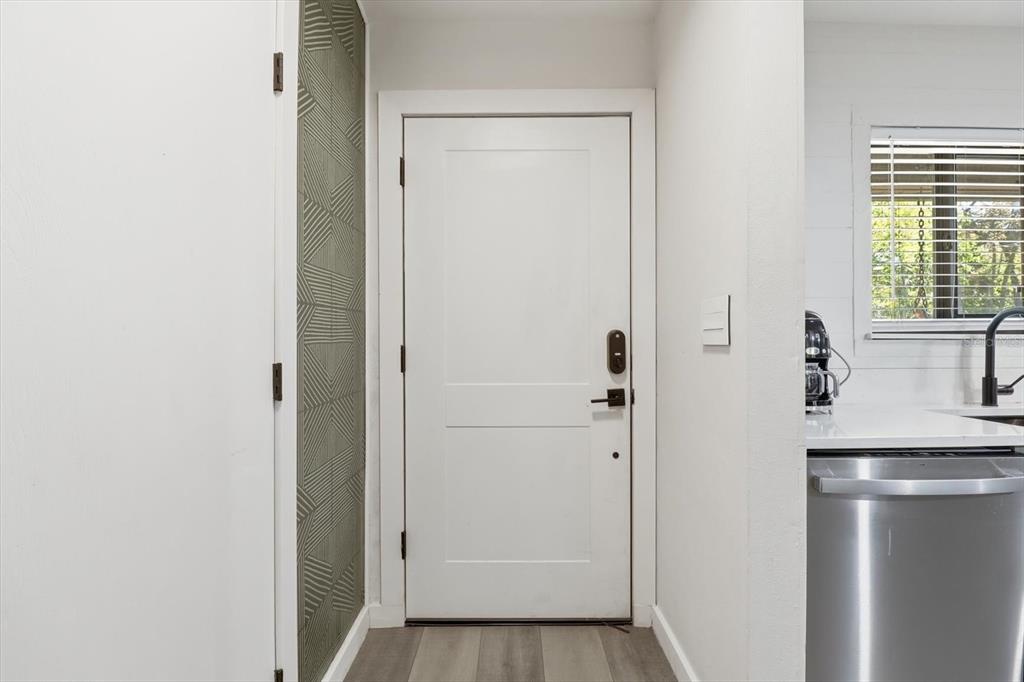 A white door with a geometric wallpaper accent wall stands next to a kitchen area — 8952 W WHITE DOGWOOD DRIVE, HOMOSASSA, FL
