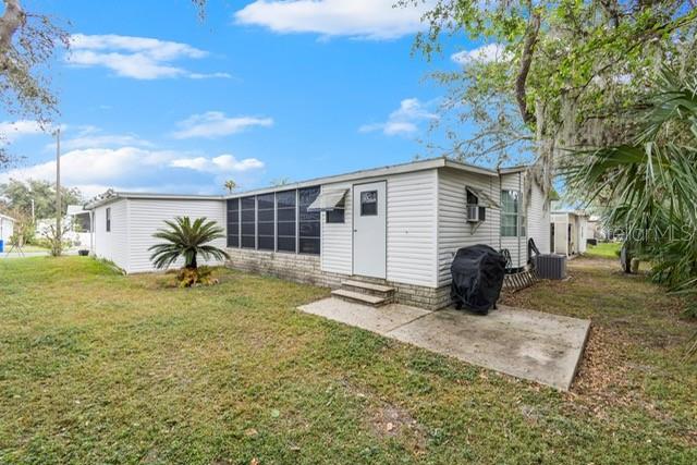 A white mobile home with a screened-in porch and a concrete patio in the yard — 34124 ESTATES LANE, WESLEY CHAPEL, FL