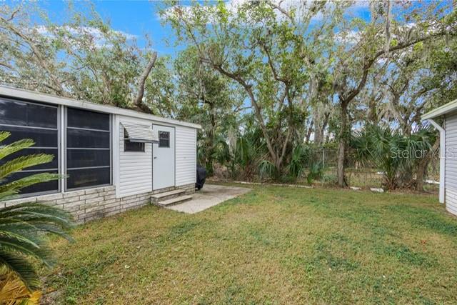 The exterior of a white mobile home features a screened-in porch and a grassy yard — 34124 ESTATES LANE, WESLEY CHAPEL, FL