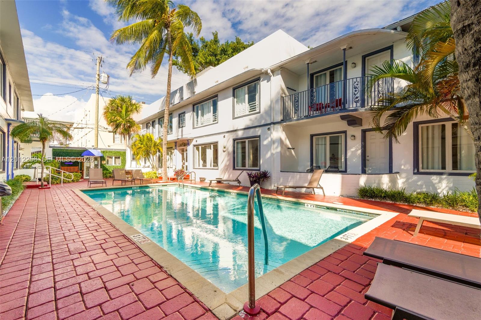 A swimming pool sits in the courtyard of a two-story white apartment building — 1540 Jefferson Ave # 2, Miami Beach FL 33139, MIAMI BEACH, FL