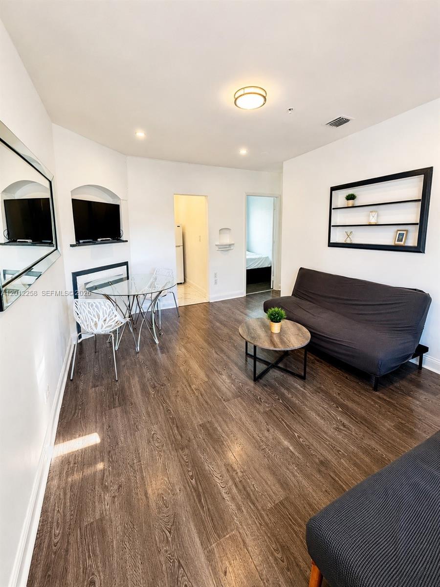 This living room features dark wood-look flooring, a gray sofa, and a glass dining table — 1540 Jefferson Ave # 2, Miami Beach FL 33139, MIAMI BEACH, FL