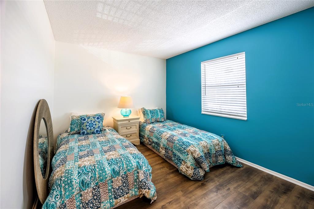 A bedroom features two twin beds, a nightstand, and a blue accent wall — 6220 AUGUSTA DRIVE UNIT 309, FORT MYERS, FL