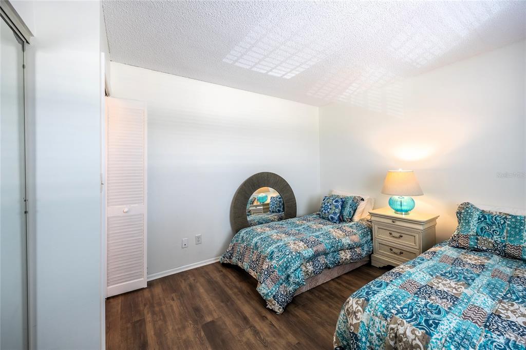 A bedroom features two twin beds with blue patterned quilts, a nightstand, and wood flooring — 6220 AUGUSTA DRIVE UNIT 309, FORT MYERS, FL