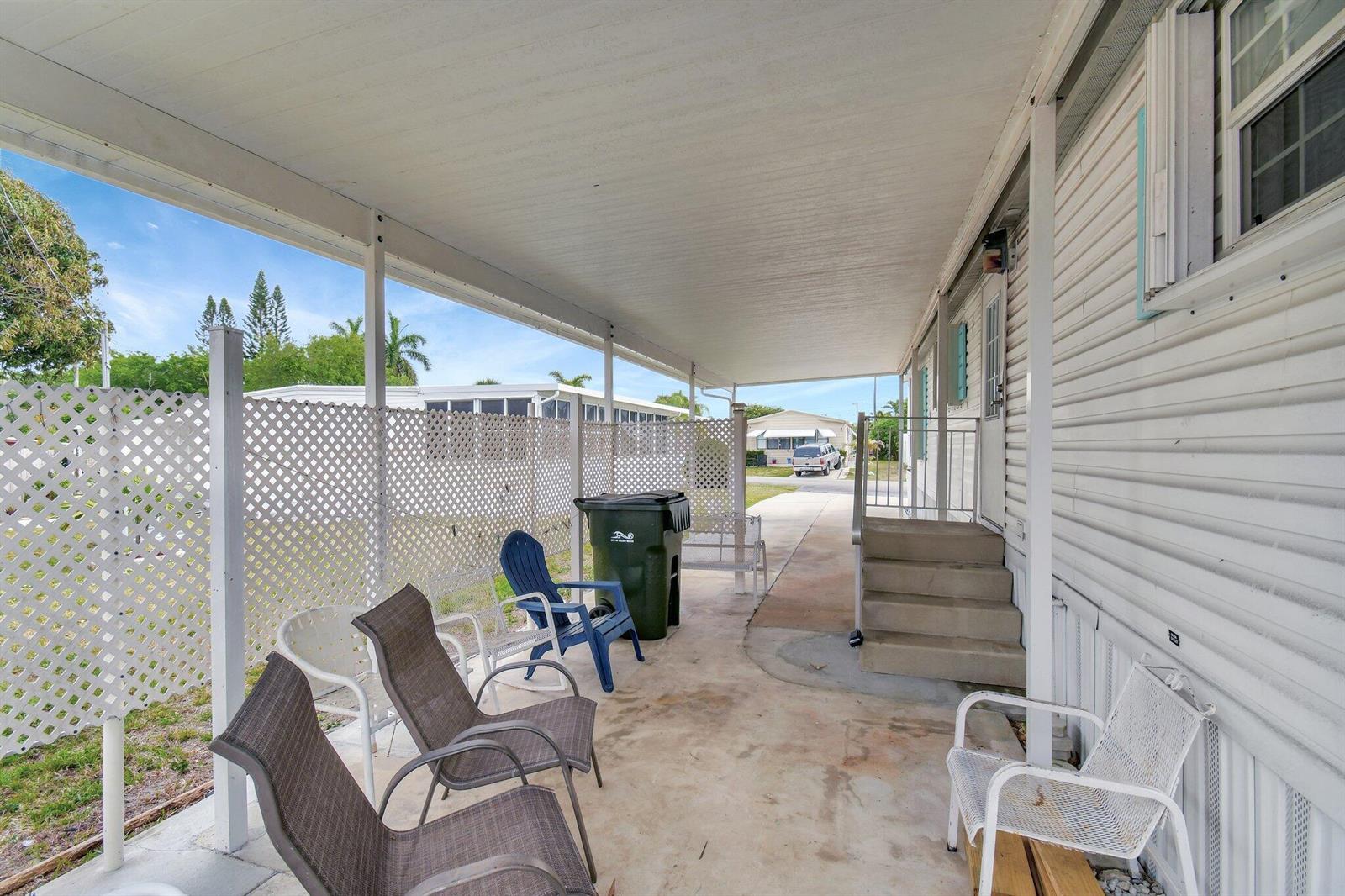 A covered patio with a concrete floor, lattice privacy screen, and several outdoor chairs — 14567 Sunset Drive, Delray Beach FL 33445, DELRAY BEACH, FL