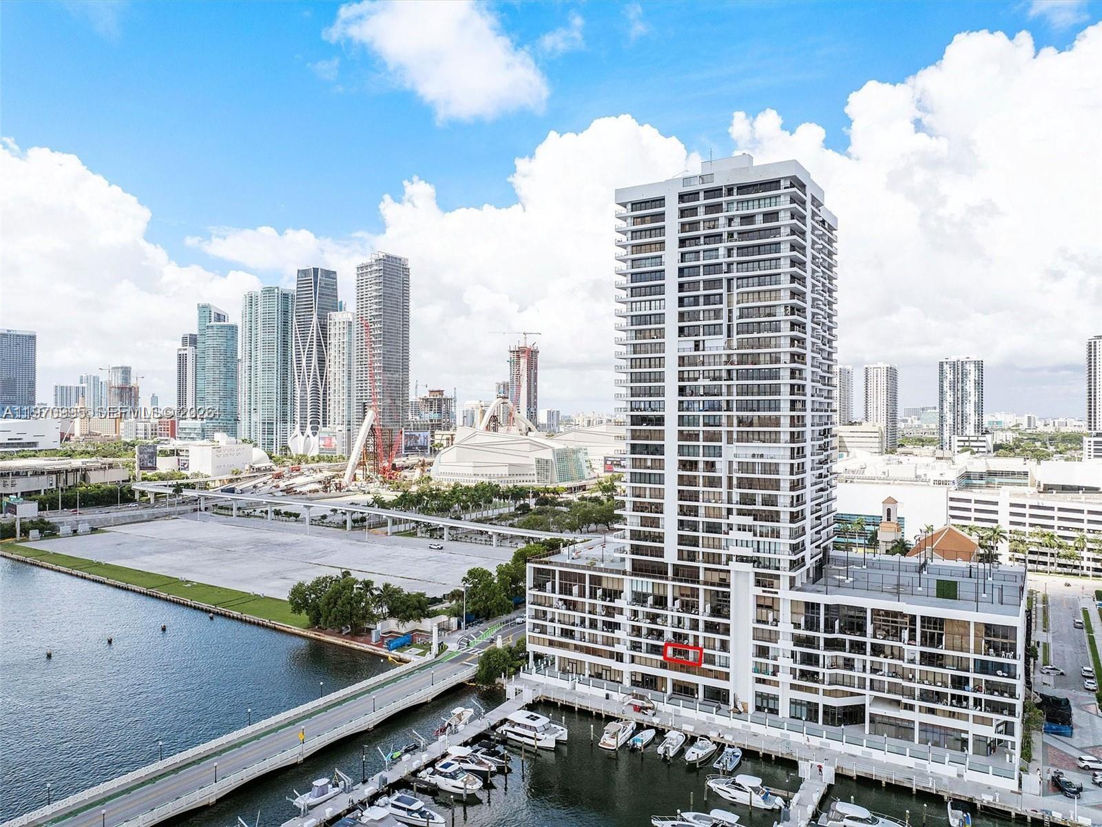 An aerial view shows a high-rise residential building with a red-outlined balcony overlooking a marina — 555 NE 15th St # 408, Miami FL 33132, MIAMI, FL