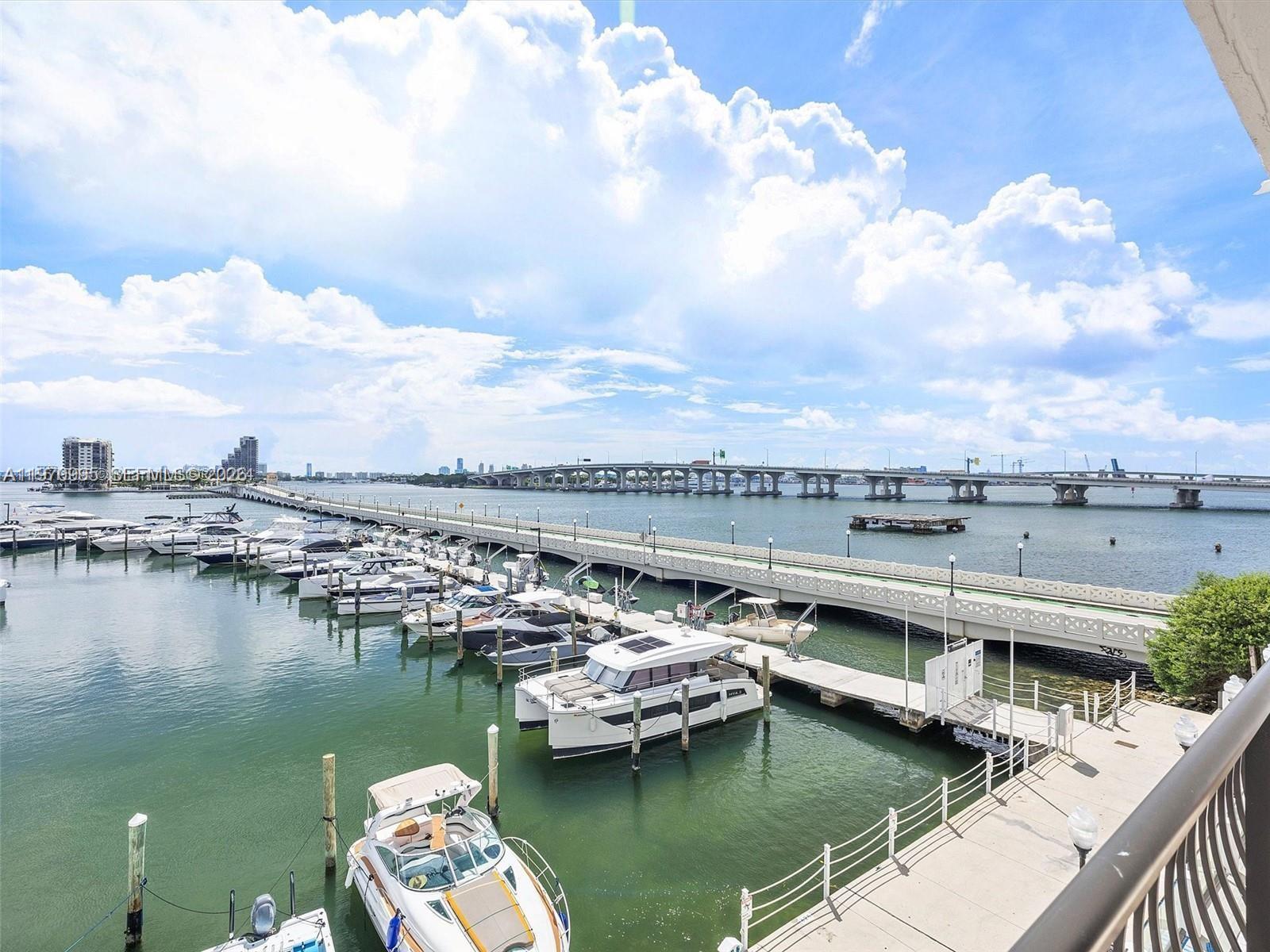 A view from a balcony overlooking a marina with docked boats and a long bridge — 555 NE 15th St # 408, Miami FL 33132, MIAMI, FL