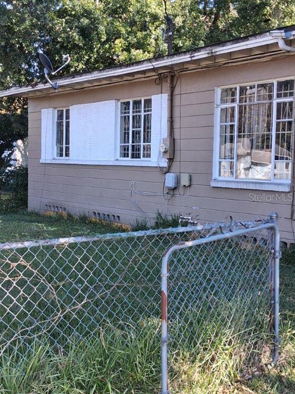 Exterior view of a tan house with white-trimmed windows, a chain-link fence, and a satellite dish — 2748 W 45TH STREET, JACKSONVILLE, FL