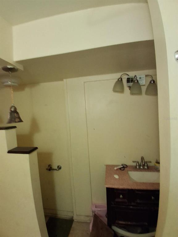 A bathroom features a vanity with a pink countertop, a sink, and three-bulb wall lighting — 2748 W 45TH STREET, JACKSONVILLE, FL