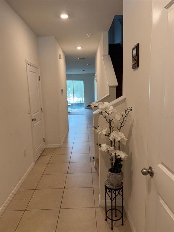 A hallway with tiled floors leads toward a glass sliding door at the far end — 3244 PLEASANT WILLOW COURT, BRANDON, FL