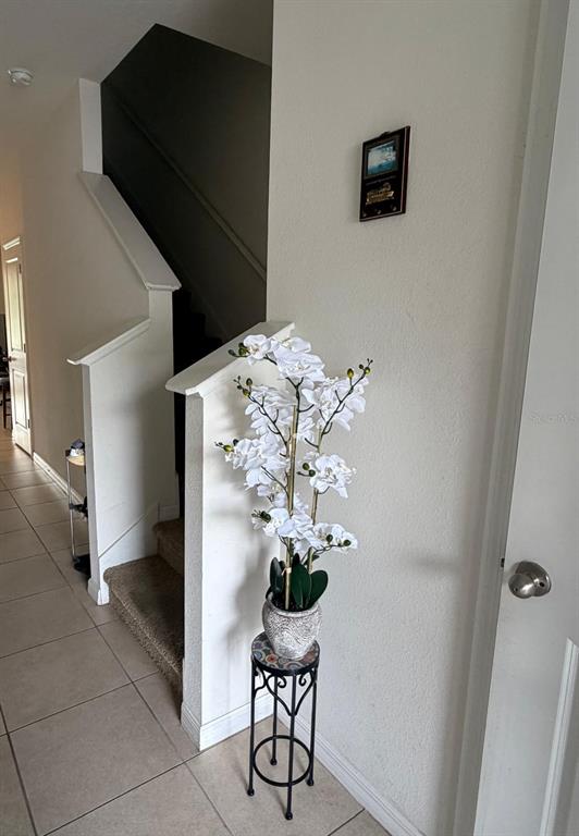 A white artificial orchid sits on a metal plant stand near a carpeted staircase — 3244 PLEASANT WILLOW COURT, BRANDON, FL