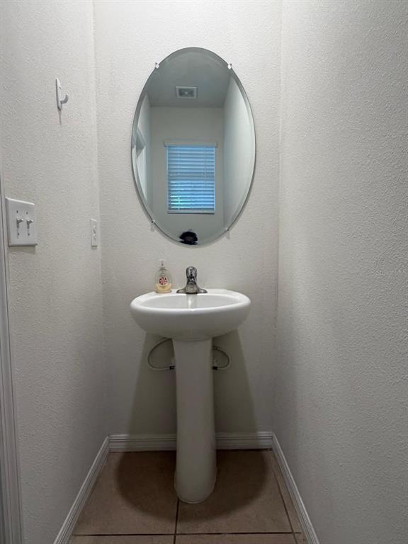 A small bathroom features a white pedestal sink, an oval wall mirror, and tile flooring — 3244 PLEASANT WILLOW COURT, BRANDON, FL
