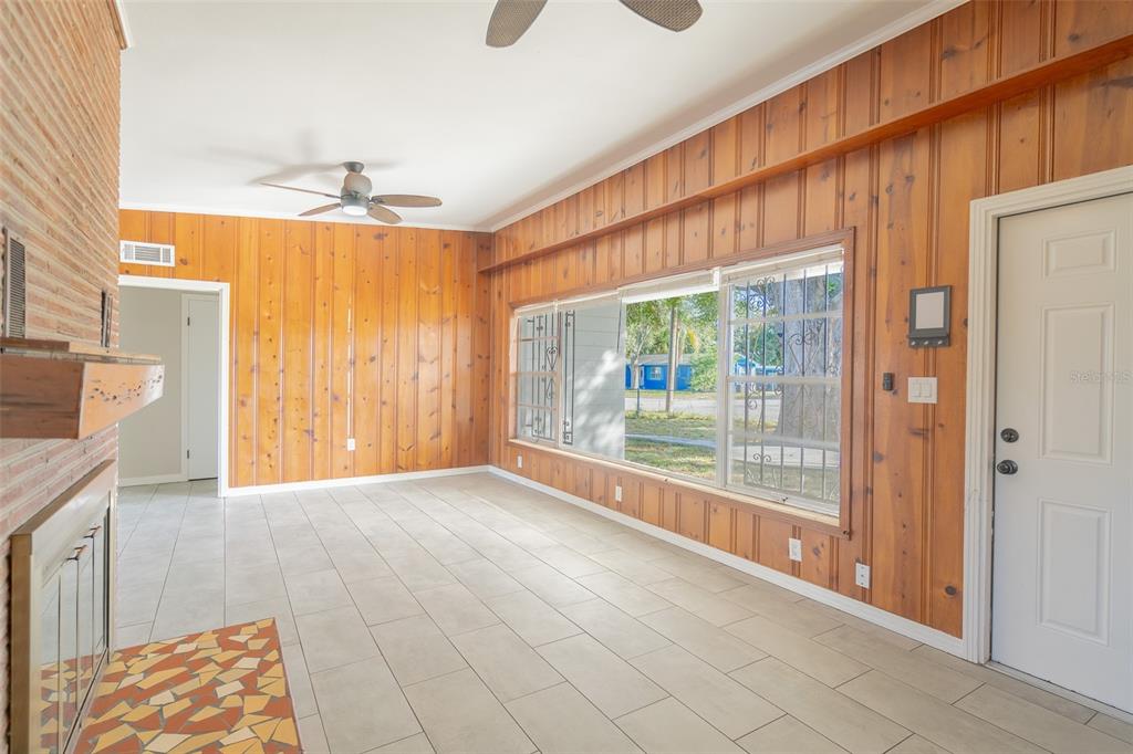 A living room features wood-paneled walls, tile flooring, a fireplace, and large windows — 495 AVENUE F SE, WINTER HAVEN, FL