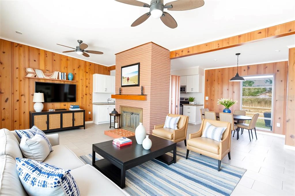 A living room features wood-paneled walls, a brick fireplace, and a dining area beyond — 495 AVENUE F SE, WINTER HAVEN, FL